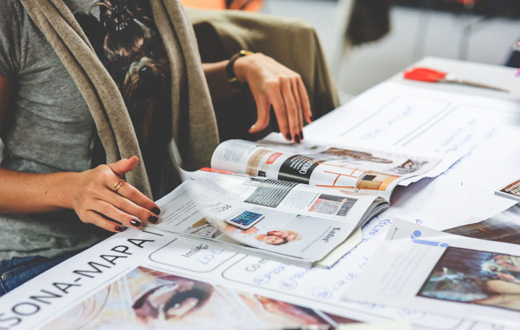 Woman reading a magazine on a table full of papers