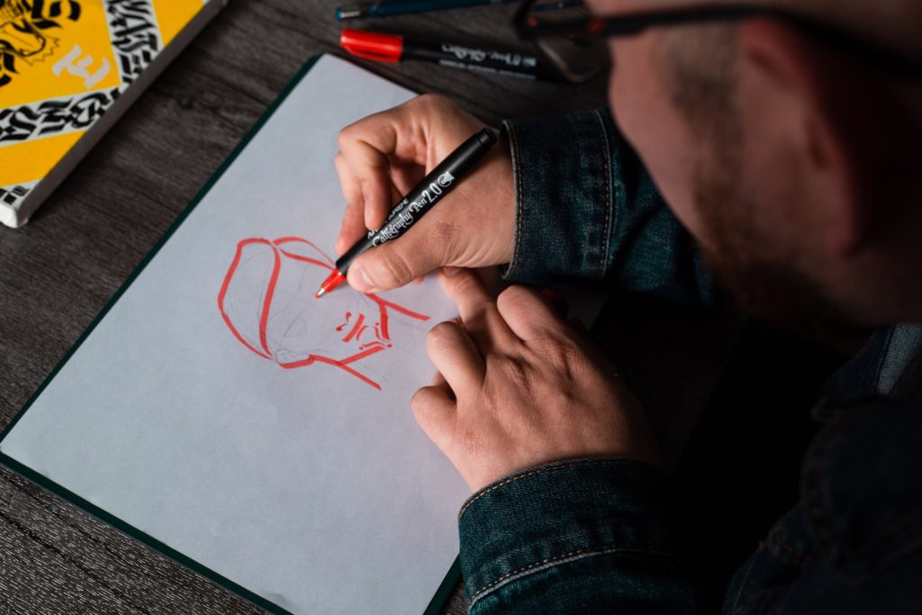 man drawing face on paper colouring